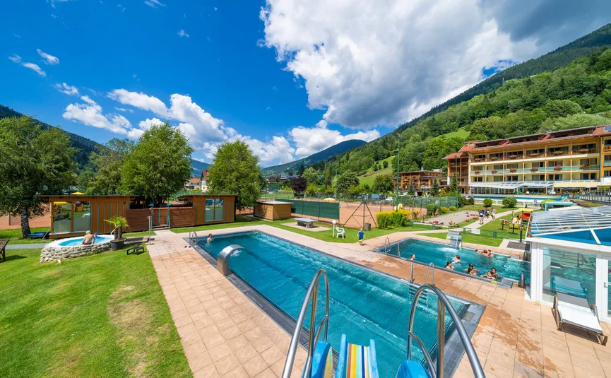 Außenpools und Spielbereiche in einer Bergferienanlage bei sonnigem Wetter