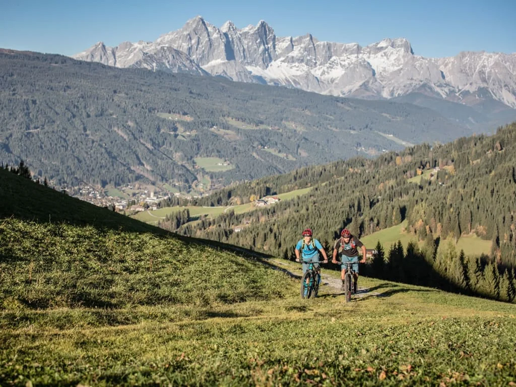 Zwei Radfahrer fahren auf einem Bergweg mit Blick auf die Dolomiten