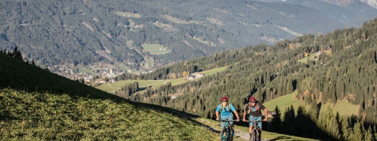 Zwei Radfahrer fahren auf einem Bergweg mit Blick auf die Dolomiten