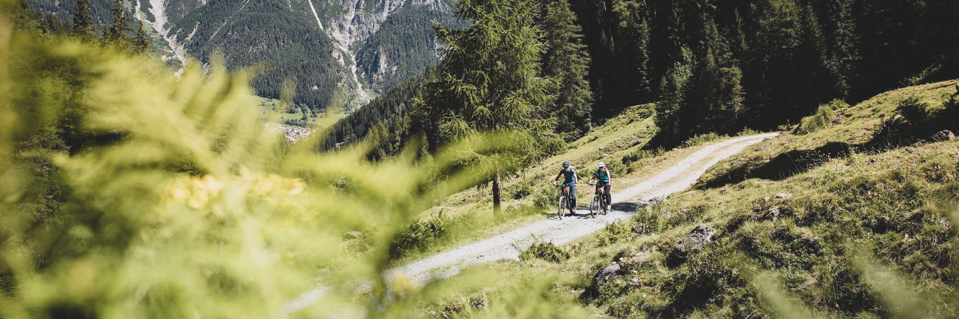 Hotel Arpuria | Hidden Luxury Mountain Home **** © TVB St. Anton am Arlberg - Patrick Bätz Two cyclists on forest trail with mountain scenery in the background