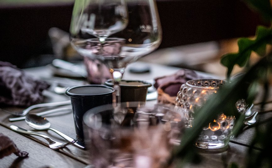 Hotel Walliserhof © Martina Wunderle Gedeckter Esstisch mit Gläsern und Kerze vor grünem Hintergrund