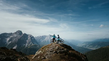 Südtirol von seiner schönsten Seite © Desire Lines - Tobias Dörr Zwei Mountainbiker auf einem Berggipfel mit Ausblick auf Gebirge