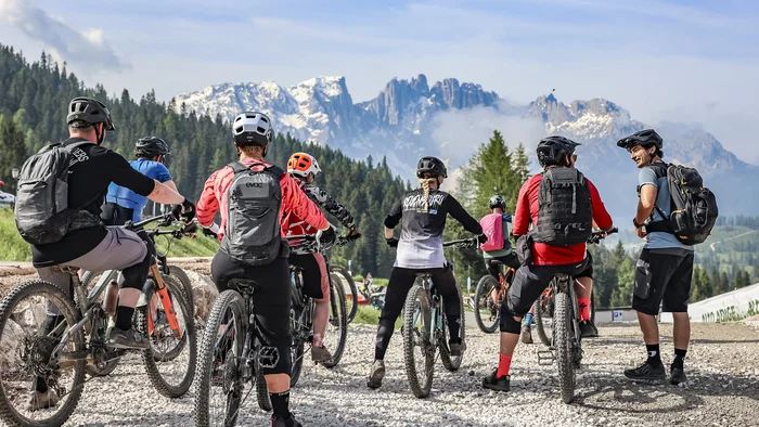 Gruppe von Mountainbikern mit Helm und Rucksäcken vor Berglandschaft