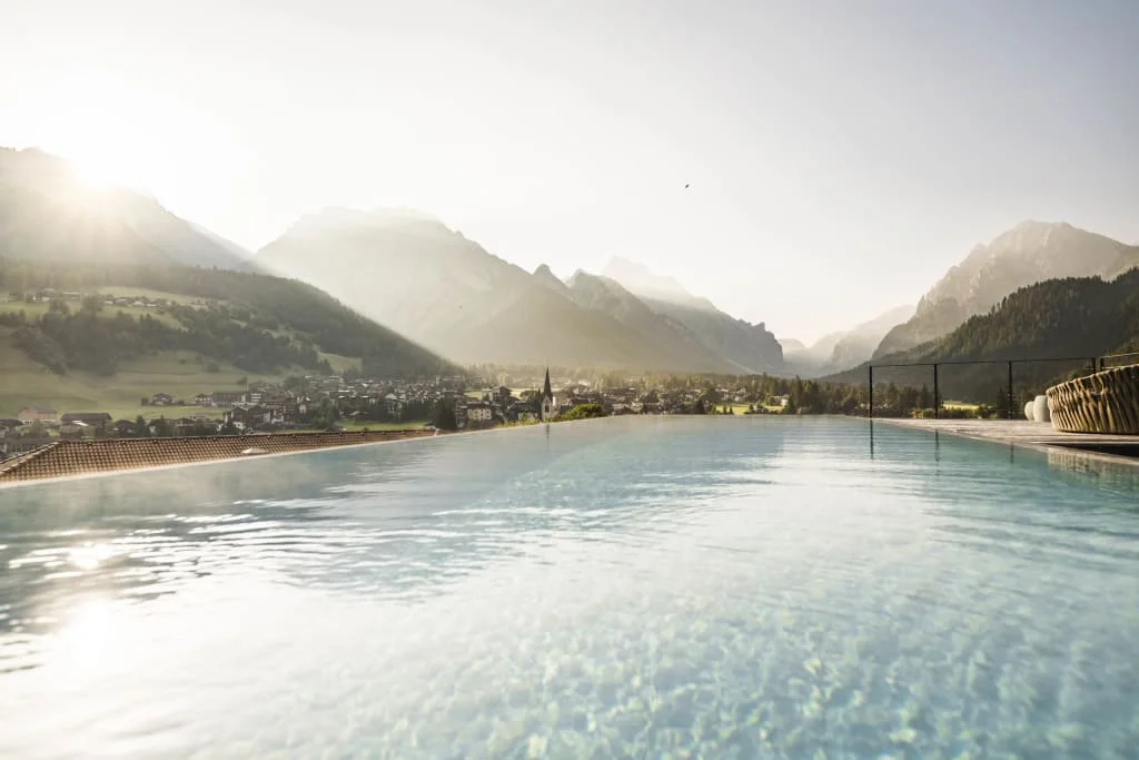 Infinity pool overlooking mountains and village in sunlight