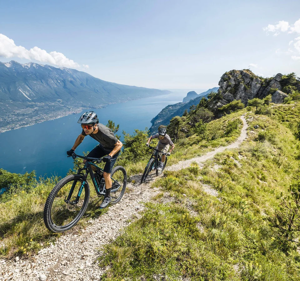 Zwei Mountainbiker auf einem Bergpfad mit Seeblick