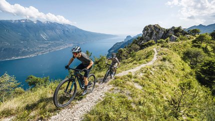 Zwei Mountainbiker auf einem Bergpfad mit Seeblick