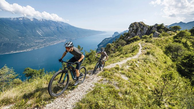 Zwei Mountainbiker auf einem Bergpfad mit Seeblick