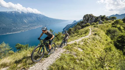 Zwei Mountainbiker auf einem Bergpfad mit Seeblick