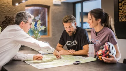 Three people discussing and pointing at a map on a table