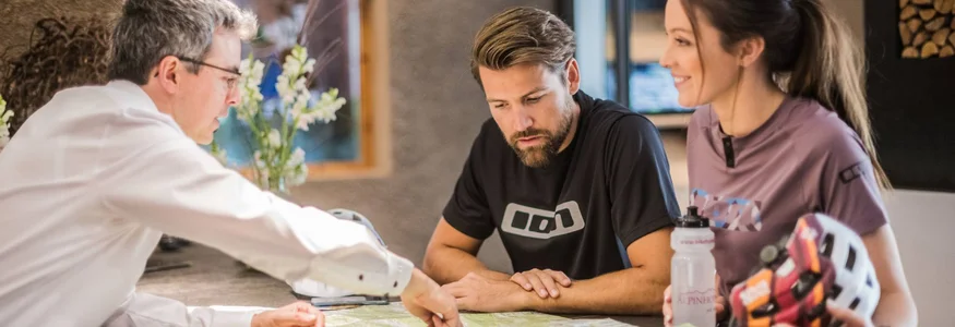 Drei Menschen besprechen und zeigen auf eine Landkarte auf einem Tisch