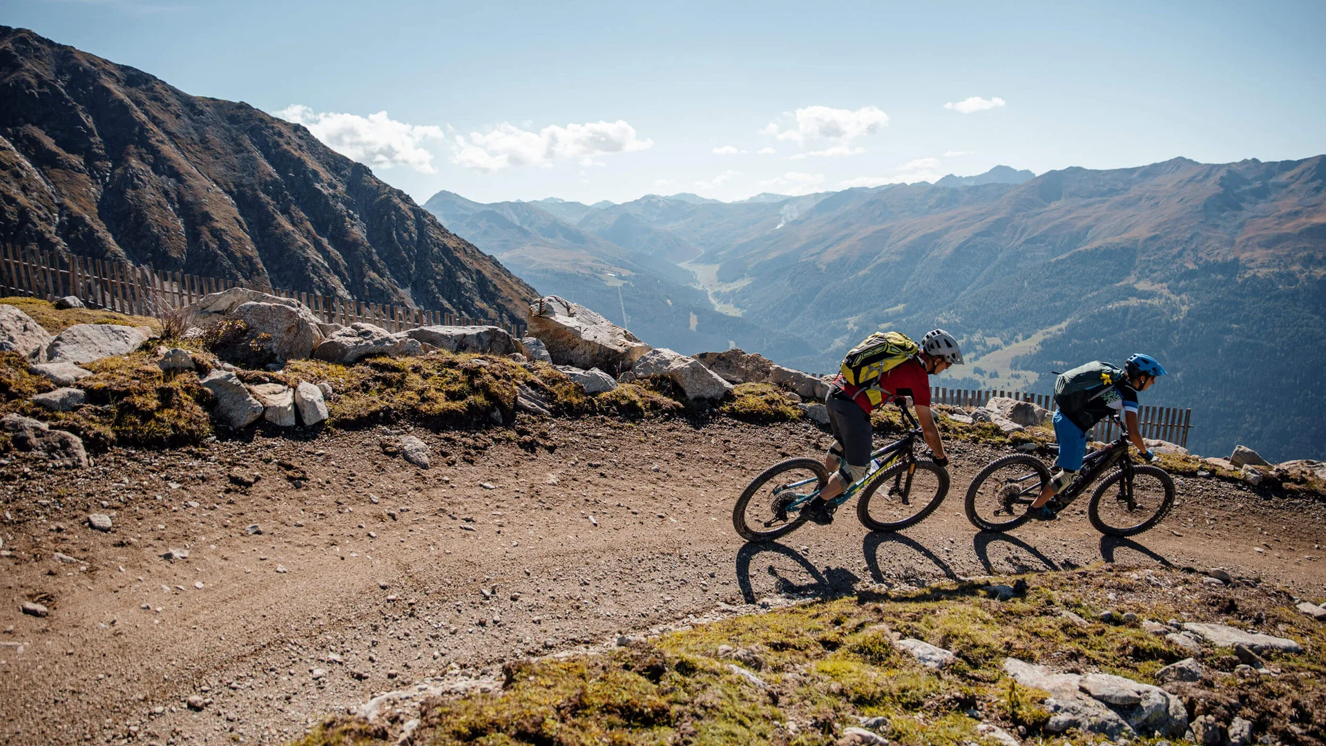 Zwei Mountainbiker auf einem Bergpfad mit Aussicht auf Berge