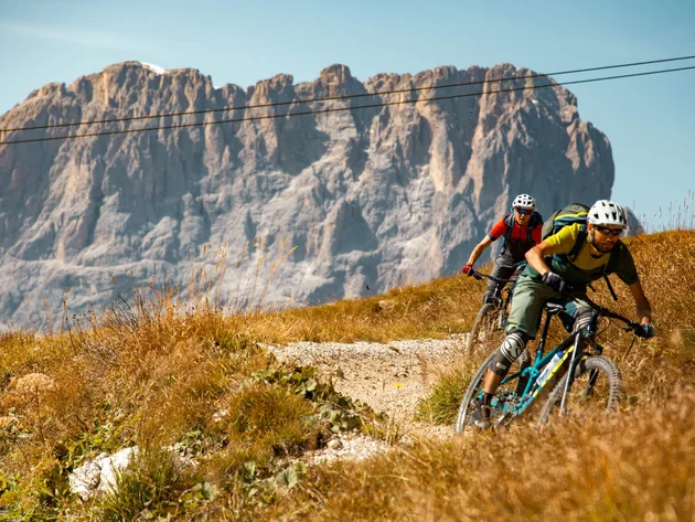 Zwei Mountainbiker fahren auf einem Bergweg vor Felsen