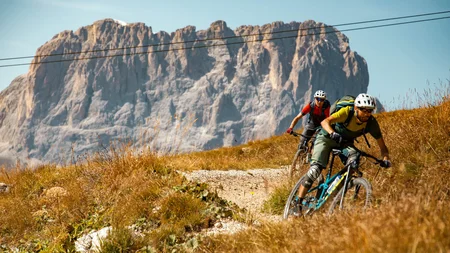 Zwei Mountainbiker fahren auf einem Bergweg vor Felsen
