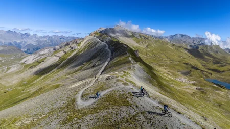 Mountainbiker auf einem Höhenweg in alpiner Landschaft bei klarem Himmel