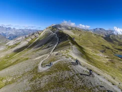 Mountainbiker auf einem Höhenweg in alpiner Landschaft bei klarem Himmel