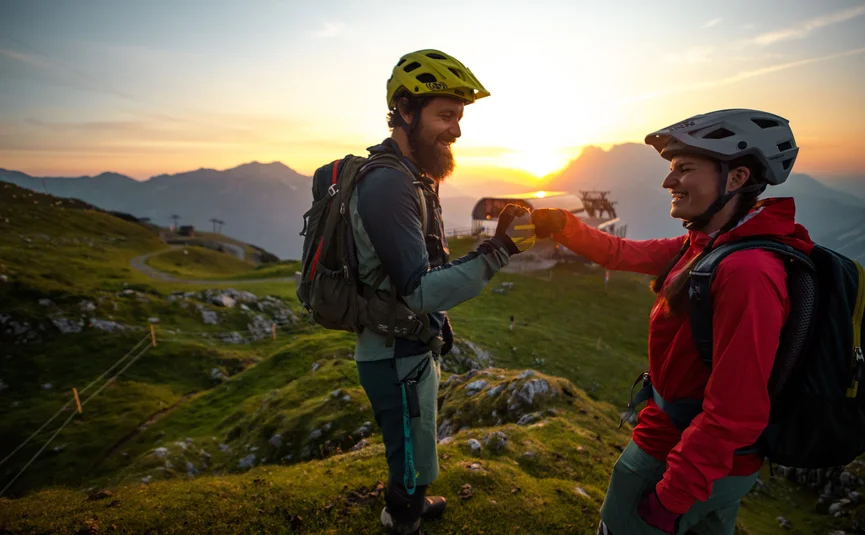Two mountain bikers fist bumping at sunset in the mountains
