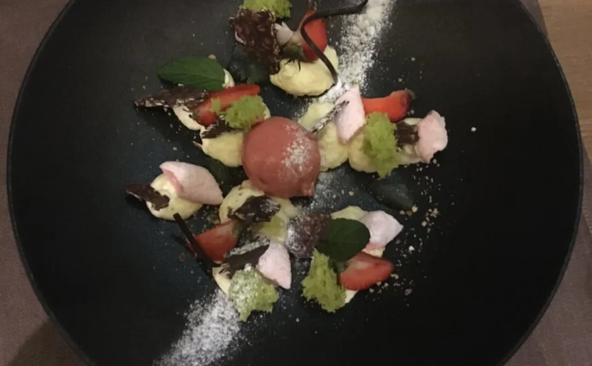 4 Tage Genuss-Skifahren auf der Sonnenseite der Zugspitze 2026-7 Kunstvoll angerichtetes Dessert mit Erdbeersorbet, Sahne und Minzblättern auf schwarzem Teller