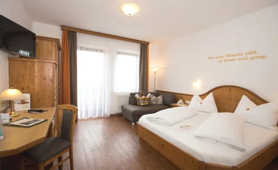 Helles Hotelzimmer mit Holzmöbeln, Doppelbett und Sofa