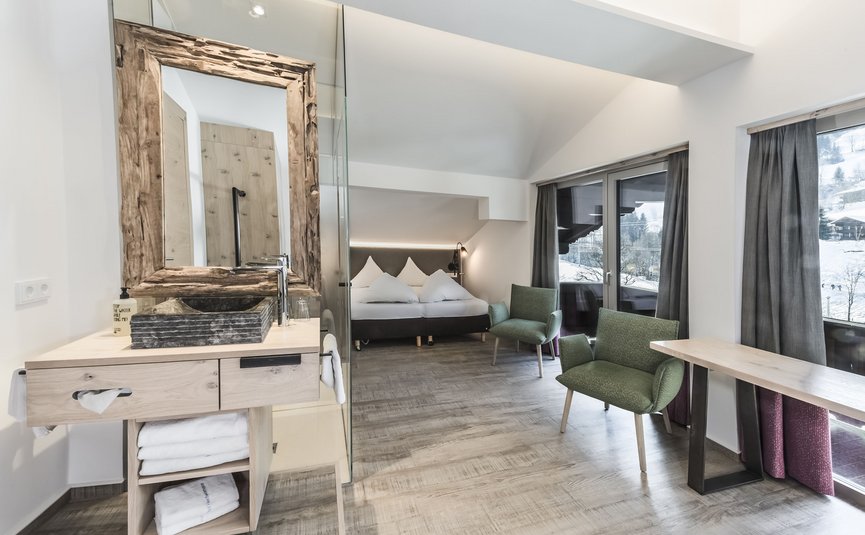 Modernes Hotelzimmer mit Bett, Waschbecken und Sitzbereich mit Bergblick