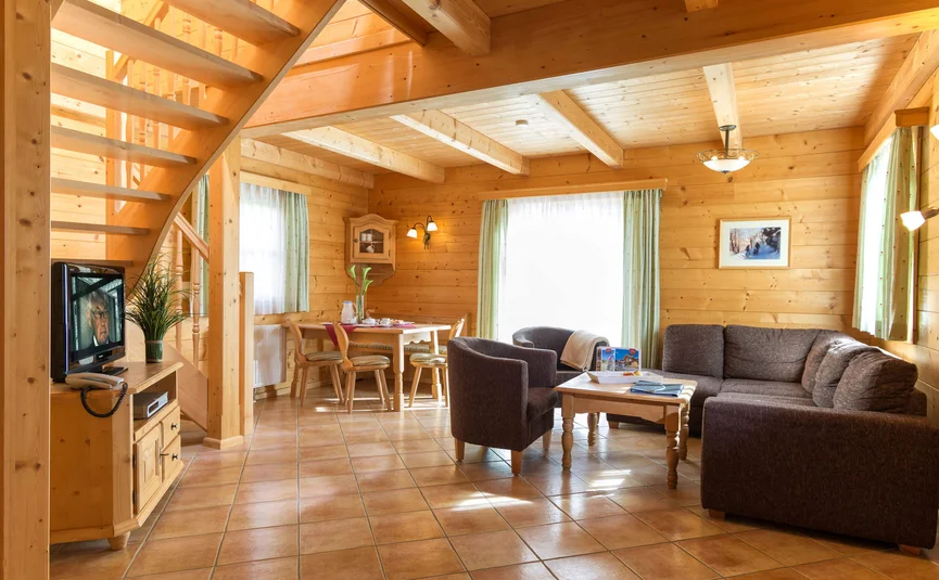 Lichte woonkamer in houten huis met bruine meubels en trap