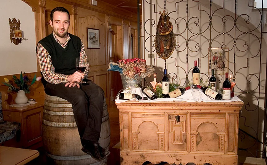 Man zit op wijnvat met wijnglazen en flessen op houten kast