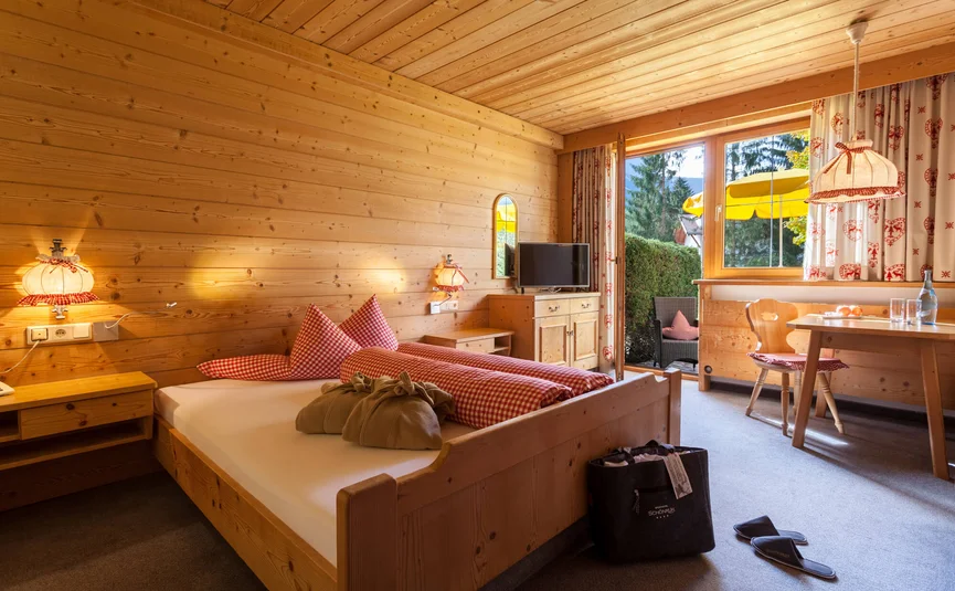 Cozy wooden bedroom with double bed and terrace in daylight