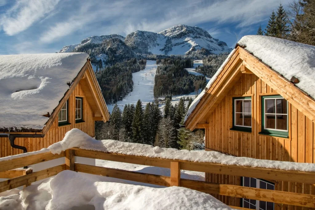 Mid Week 4 Nächte Verschneite Holzhäuser mit Blick auf eine Skipiste und bewaldete Berge