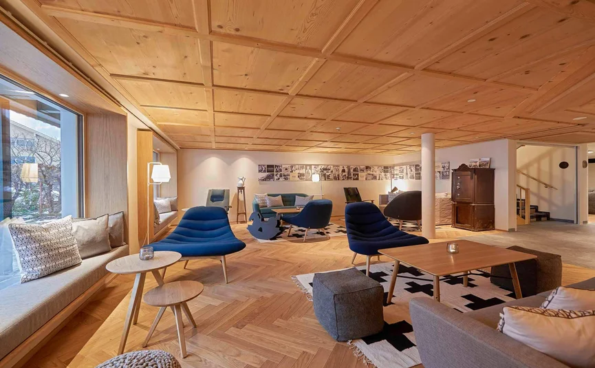 Gezellige lounge met houten vloer, blauwe stoelen en grote ramen
