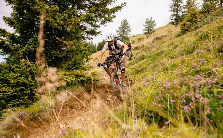Zwei Mountainbiker fahren einen schmalen Waldweg bergab
