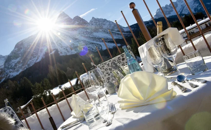 Zonnige tafel gedekt met glazen en besneeuwde bergen op de achtergrond
