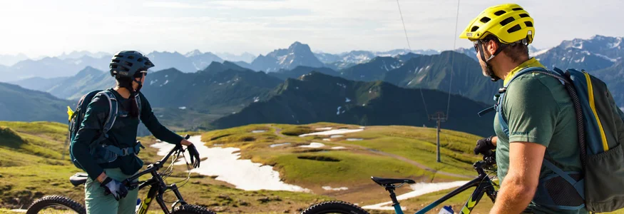 Best of Bregenzerwald © David Karg Zwei Radfahrer in den Bergen mit Blick auf schneebedeckte Gipfel und grüne Täler