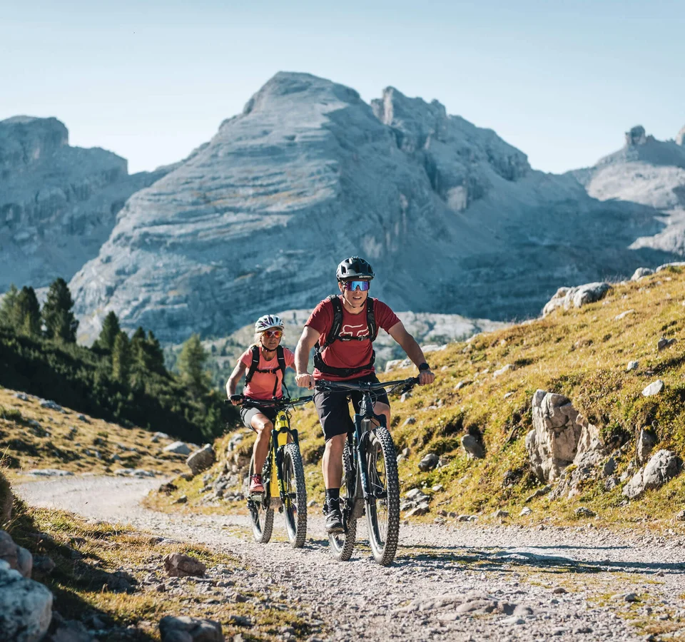 Ein Herbst-Wochenende in San Vigilio © Alex Moling Zwei Mountainbiker fahren auf einem Bergweg vor großen Bergen