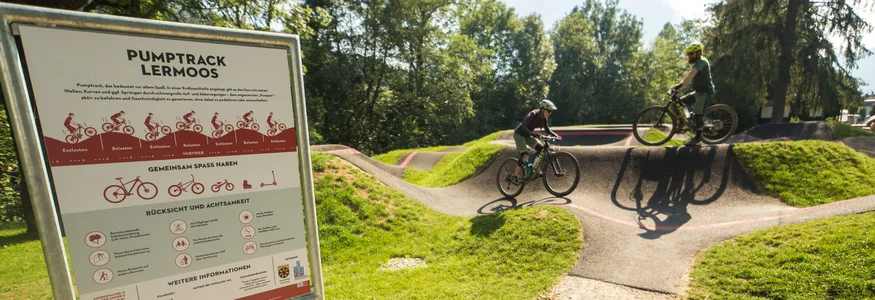 Pumptrack in Lermoos mit zwei Radfahrern und einem Info-Schild