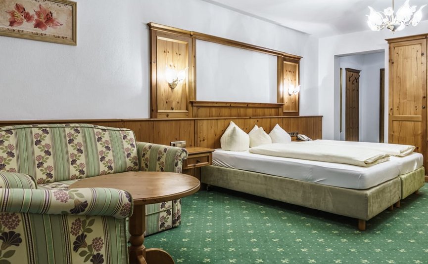 Cozy hotel room with bed, sofa, and wooden furniture