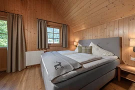 Ski Woche 7 Nächte inkl. Skipass Schlafzimmer mit großem Bett und Holzvertäfelung an Wänden und Dachschräge
