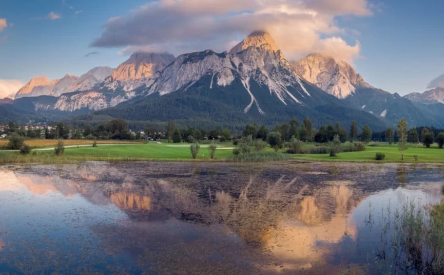 Bergpanorama bij zonsondergang met meer en wolken