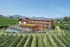 Hotel mit Weinberg und Bergen im Hintergrund bei klarem Himmel