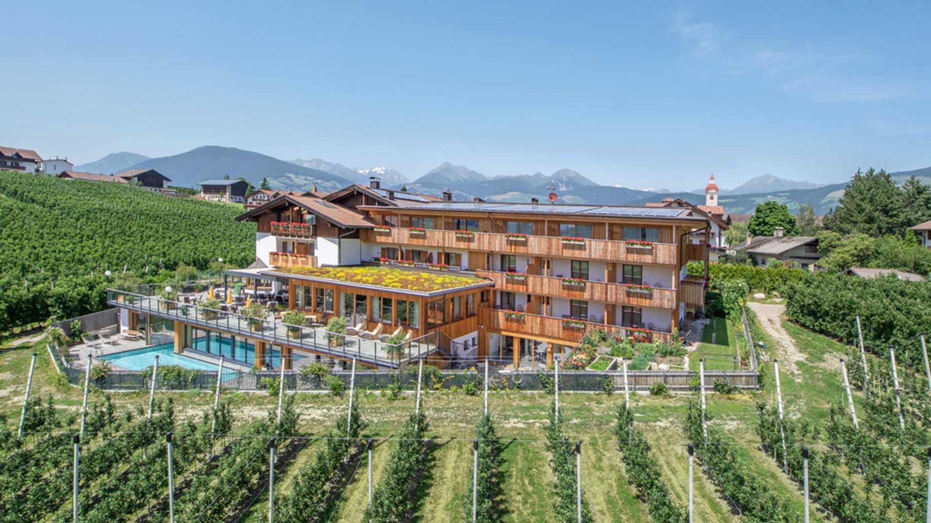 Hotel mit Weinberg und Bergen im Hintergrund bei klarem Himmel