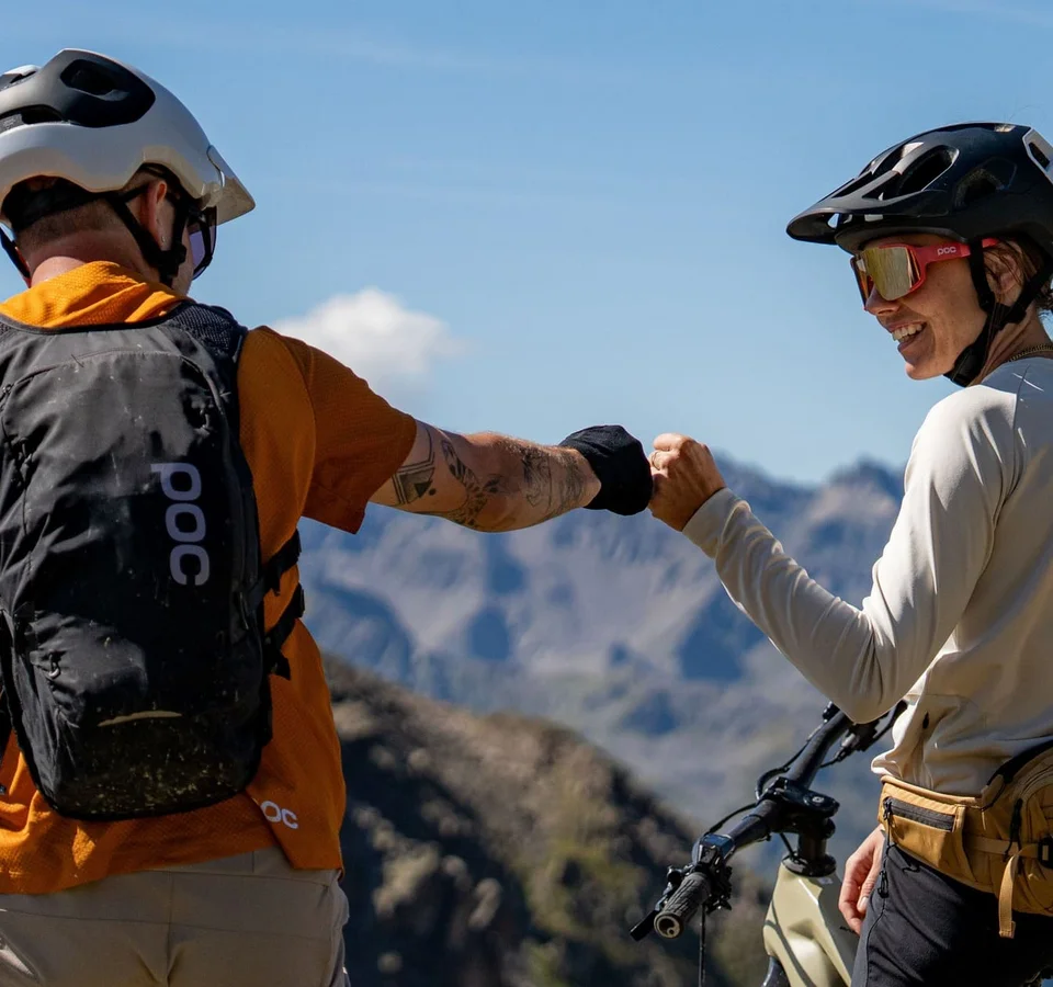 Zwei Mountainbiker mit Helm geben sich auf Berglandschaft die Faust