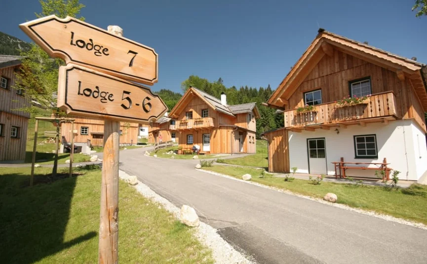 Wooden signposts for lodges in front of wooden cabins on a sunny day