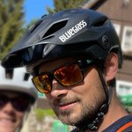 Mann mit schwarzem Bluegrass-Fahrradhelm und Sonnenbrille im Freien