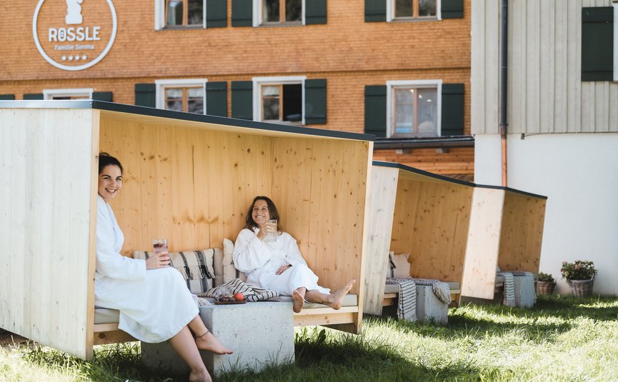 Two women in bathrobes relaxing in wooden outdoor booths