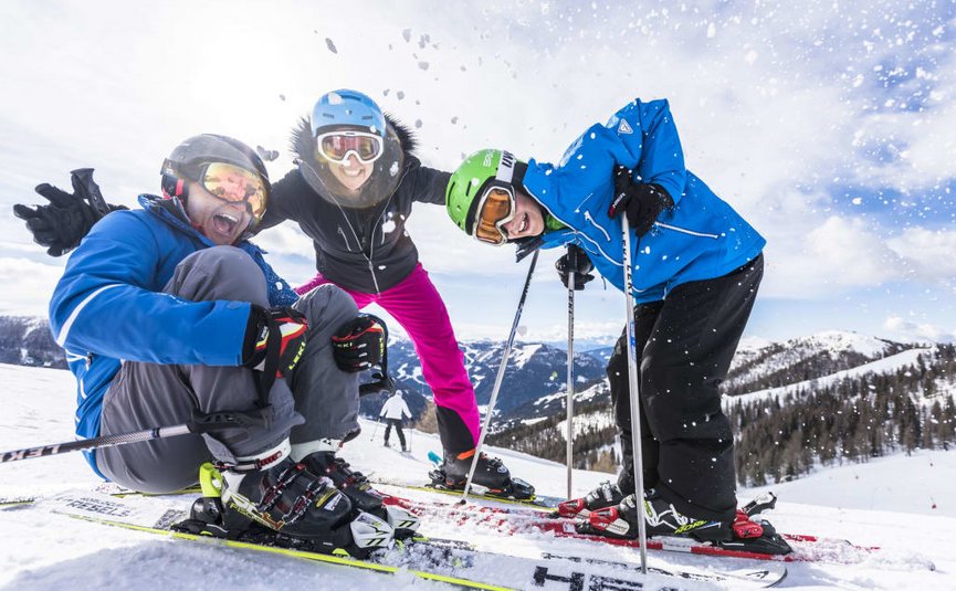 Drei fröhliche Skifahrer posieren im Schnee auf einer Bergpiste