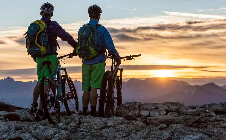 Zwei Mountainbiker betrachten Sonnenuntergang über Bergen