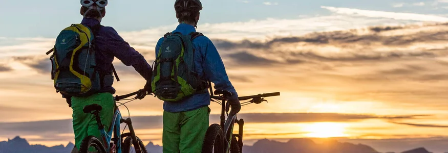 Zwei Mountainbiker betrachten Sonnenuntergang über Bergen
