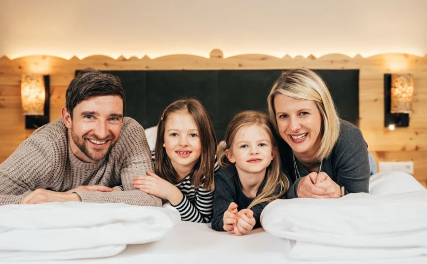 Gelukkig gezin met twee dochters liggend op een bed in een gezellige kamer