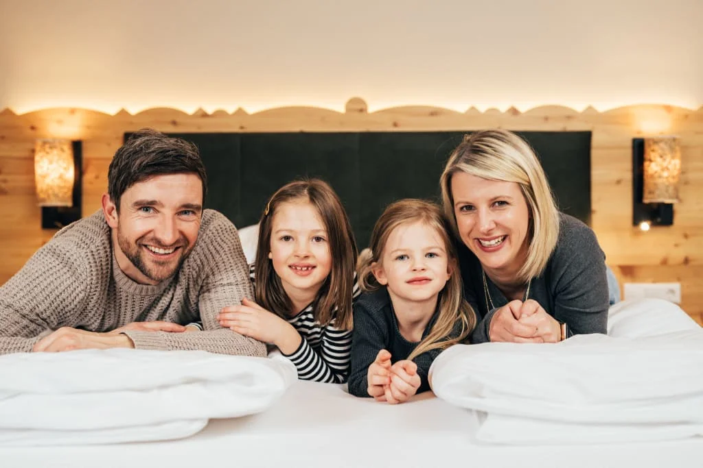 Zeit für kleine Entdecker Gelukkig gezin met twee dochters liggend op een bed in een gezellige kamer