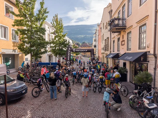 Das war die bike festa Südtirol in Brixen © Brixen Tourismus - bike festa Südtirol 2026 Radfahrer versammeln sich unter einem SCOTT-Bogen in einer gepflasterten Altstadtstraße