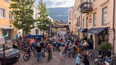 Das war die bike festa Südtirol in Brixen © Brixen Tourismus - bike festa Südtirol 2026 Radfahrer versammeln sich unter einem SCOTT-Bogen in einer gepflasterten Altstadtstraße
