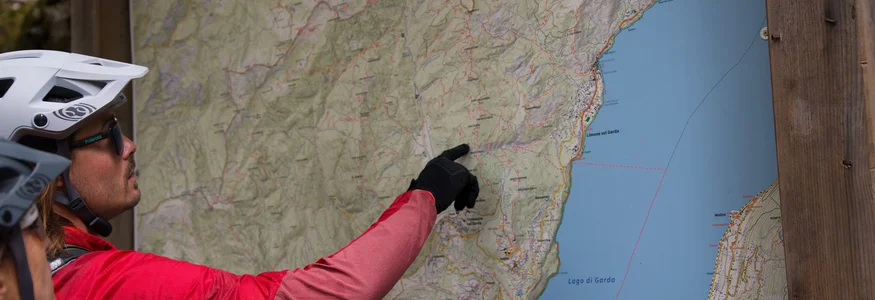 Personen mit Fahrradhelm betrachten eine Wanderkarte am Gardasee